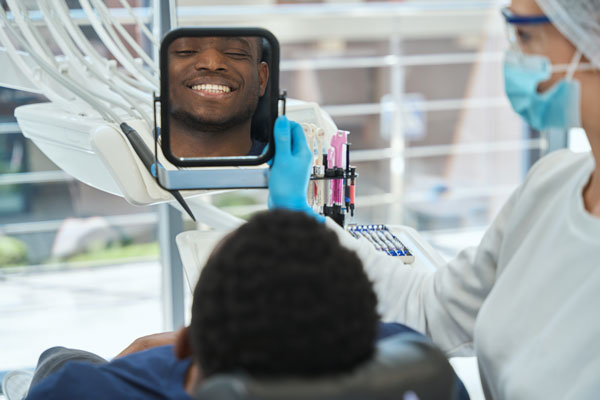 Patient looking at his white teeth after teeth whitening treatment at Quicksmiles